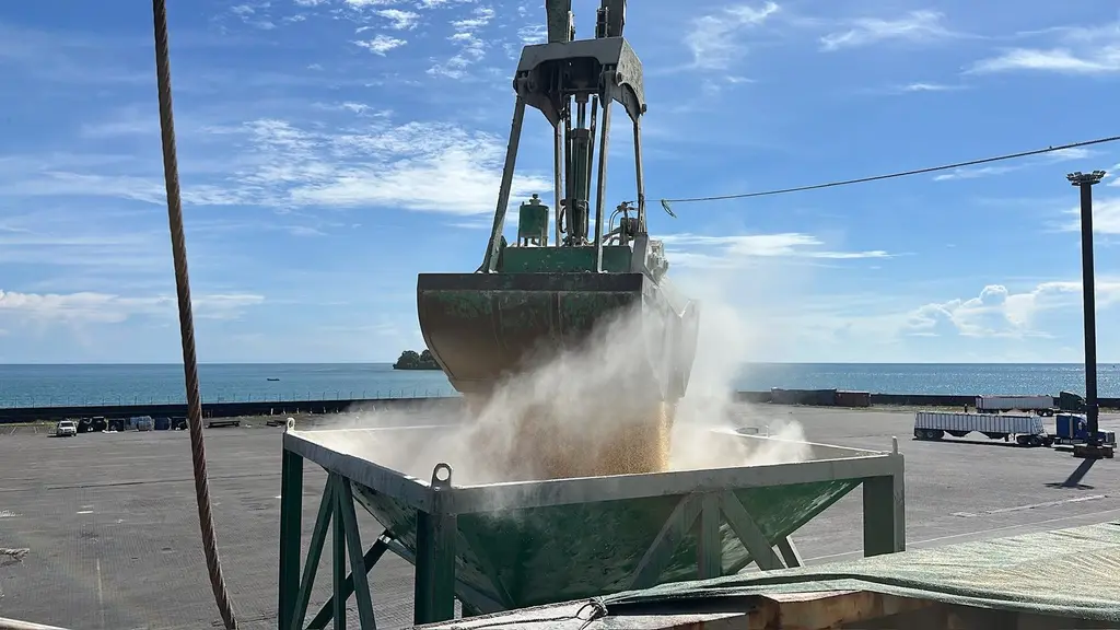 Grab discharging bulk cargo into a hopper by the sea