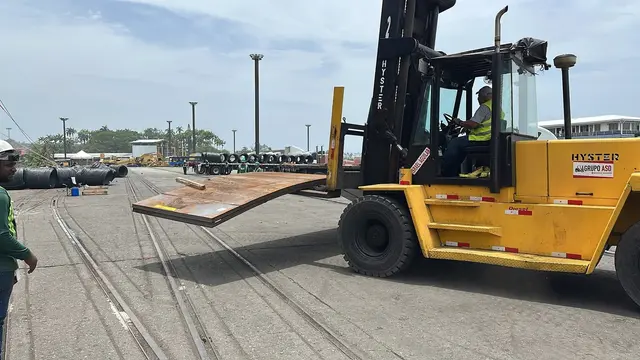 Heavy forklift carrying a steel plate across the port