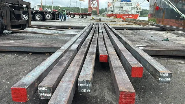 Square steel billets laid out on the dock next to the vessel