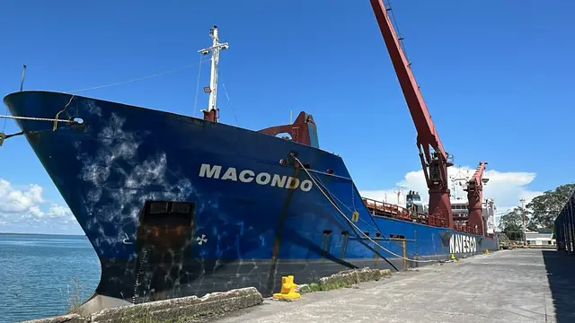 General cargo vessel moored alongside the pier, with sea and blue sky